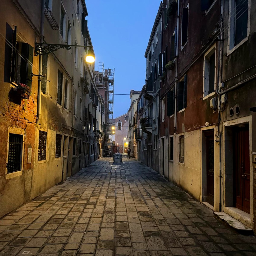 A lantern-lit street at blue hour with an old well