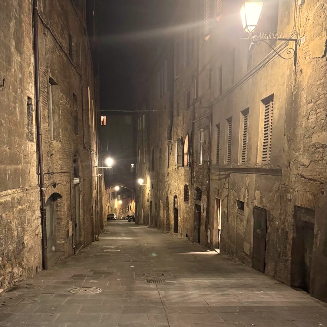 A quiet stone street at night, lit by a single lantern
